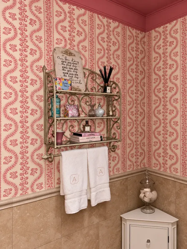 Ornate powder-room shelf layered with personal keepsakes and monogrammed towels